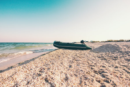 Inflatable boat on the beach. Sea coast. Beautiful sunset by the ocean. Motor boat on the shore.の写真素材