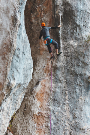 A man in helmet climbs the rock. Climbing in nature. Fitness outdoors. Active lifestyle. Extreme sports. The athlete trains on a natural relief. Training in a picturesque place. Climbing in Turkey.の写真素材