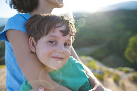 Portrait of a boy. Mom hugs her son. A woman spends time with a child in nature. A cute kid is sitting on my mother's hands.の写真素材