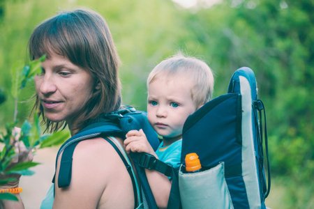 A boy is sitting in a backpack. The kid is traveling with his parents. Climbing with a child. The...