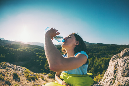 A woman is drinking water at the top of a mountain.の写真素材