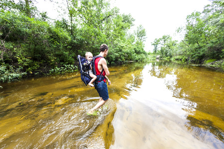 father and child go along the riverbed during the flood in Asia. travel dad with a child through the forest.の写真素材