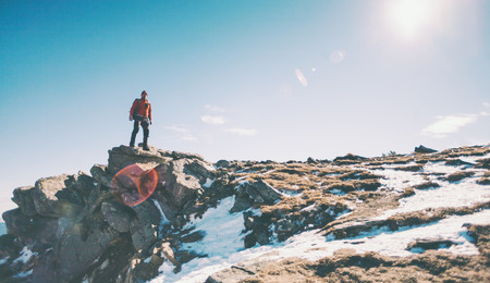 Climber with a backpack on top on a Sunny day. A man went up on the mountain, people traveling through the beautiful wilderness, man climbed to the top of a mountain and enjoying his success.の写真素材