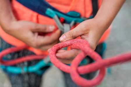 A climber knits a knot. A woman prepares to climb a climbing route. Insurance and safety in rock...