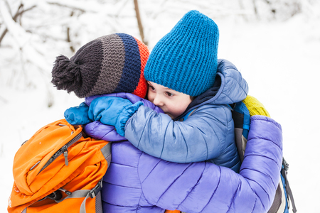The kid hugs Mom. A boy and his mother are walking in the winter forest. A child kisses his mother. The woman supports her son. Motherhood.の写真素材