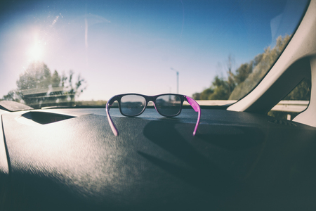 Dashboard and car windshield. View from the passenger seat of the car. Road. Inside the vehicle. Glasses are on the dashboard.の写真素材