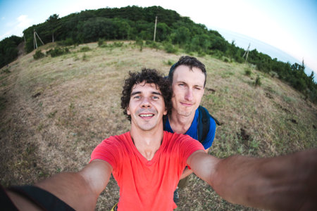 Selfie of two men. Friends in the nature. Guys in the background of the mountains. Fisheye lens.の写真素材