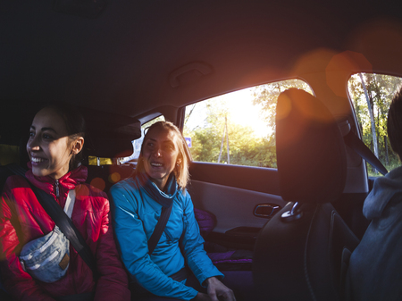 Two women in the back seat of a car. Girlfriends are hitchhiking. Passengers during a long trip. Travel by car.の写真素材
