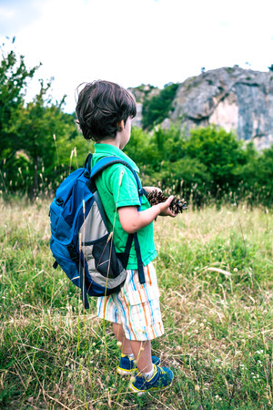 Child with a backpack in the forest. The boy walks along the mountain path. Active vacations. Traveling with children. The kid is studying nature.の写真素材