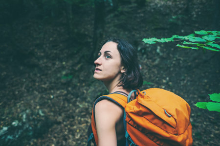 The girl is walking through the forest. A young woman with a backpack travels through picturesque...