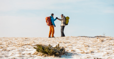 Two men in a winter hike. Friends travel with backpacks in scenic spots. Climbers on the climb. Travelers against the sky. Hiking in the mountains.の写真素材
