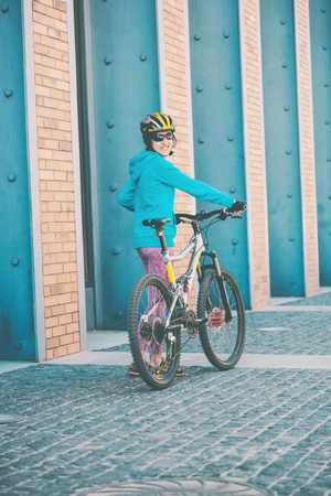 Girl with a bicycle. A woman stands near a bicycle on a city street. Active lifestyle. Smiling brunette.の写真素材