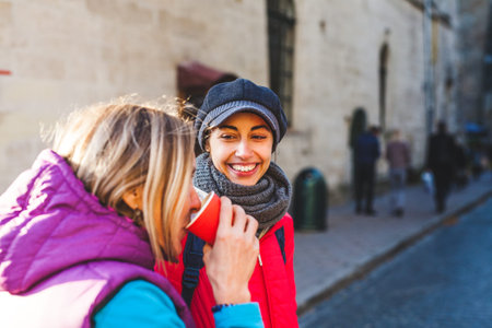 Two friends walking in the city. Women travel to European cities. Girls communicate on a city...