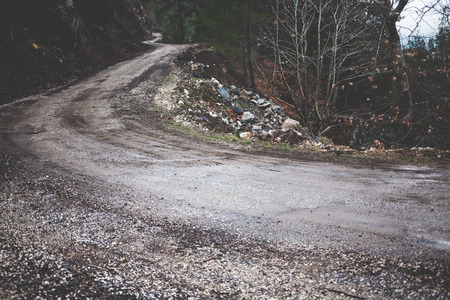 Dirt road in the mountains. Forest in early spring. Mountain trail on a rainy day.の写真素材
