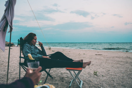 Woman drinking wine on the shore. The girl enjoys the sunset on the sea. Rest on the coast.