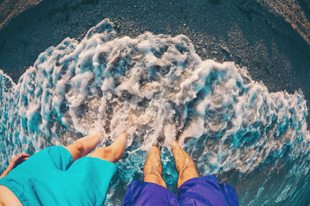 Feet in the sea. Couple on the beach. Female and male feet in the water. Ocean waves.の写真素材