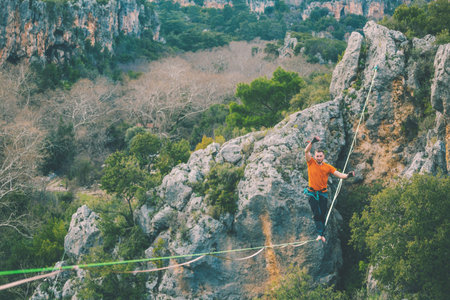 A man is walking along a stretched sling. Highline in the mountains. Man catches balance....