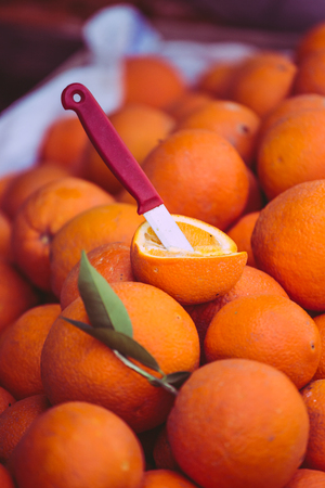 Ripe oranges in boxes. Harvesting citrus fruits. Fruit and vegetable market. Turkish bazaar. A knife cut orange.の写真素材