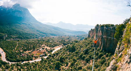 Highline in the mountains. A man walks along a stretched sling against a cloudy sky. Highline is on the line. Ropewalker catches the balance. Equilibrium.の写真素材