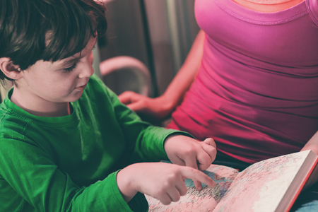 Woman and boy view a map of the world. Mother teaches the child. The boy is studying the country on the map. Preparing for the trip.の写真素材