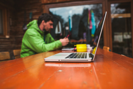 A man is sitting at a wooden table. Freelancer works for the laptop.の写真素材