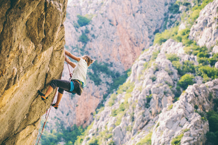 Rock climbing and mountaineering in the Paklenica National Park. A woman overcomes a challenging climbing route on natural terrain. Climber trains on the rocks of Croatia.の写真素材