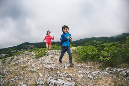 The boy runs away from his mother. The child is playing with mom. A woman is catching up with her son. Walk with mom on a mountain path. Holidays with children in nature.の写真素材