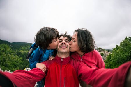 Family selfie in nature. The man and the woman walk with the son. The boy with his parents is photographed against the backdrop of the mountains. Family day.の写真素材