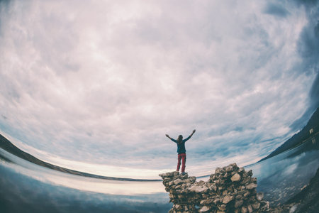 The girl stands on a pile of stones and looks at the sea. Woman resting on the sea coast. Tourist...