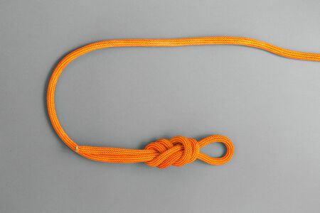 Orange climbing rope on a grey background. Safety knot. The knot the eight for safety.の写真素材