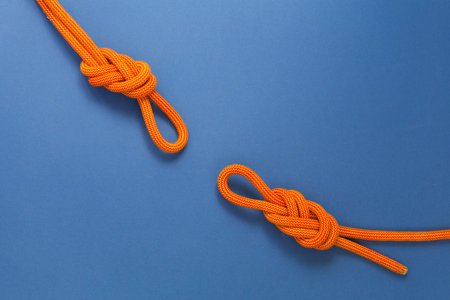 Orange climbing rope on a blue background. Safety knot. Two knots the eight for safety.