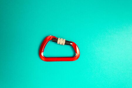 Red carabiner with clutch on a blue background. Equipment for climbing and mountaineering.の写真素材
