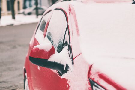 Snow covered red car. Parked vehicle close up. The machine is covered with hoarfrost. Winter snowfall.の写真素材