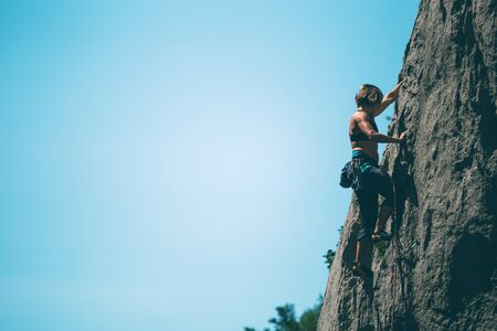 Climber overcomes challenging climbing route. A girl climbs a rock. Woman engaged in extreme sport. Extreme hobby.の写真素材