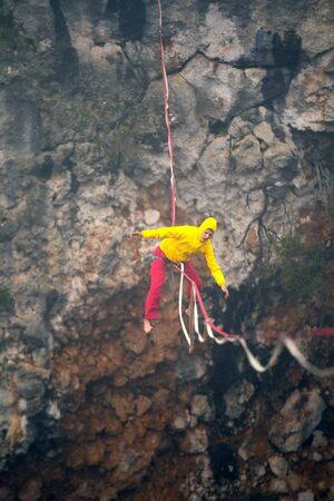 girl falls on a stretched sling. Highline in the mountains. woman lost her balance. Speech tightrope walker in nature. Highliner hanging on a rope. Fall athlete.の写真素材