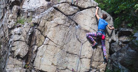 The girl climbs the granite rock. Rock climber trains on natural terrain. Extreme hobby.の写真素材