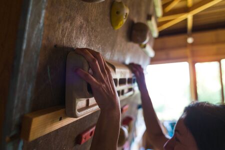Climbing equipment for finger training. Female hands on a fingerboard. The woman is pulling up. Girl hanging on a fingerboard. Rock climber warms his fingers.の写真素材