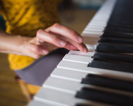 A woman learns to play the piano. The girl makes keys. Music studio. Female fingers on black and white keys.の写真素材