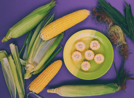 A plate with corn on a purple background. Corn slices. Cereal product. A dish of corn. Summer...