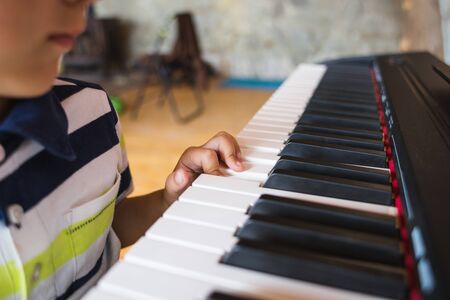 A child learns to play the piano. The boy makes keys. Music studio. Children's fingers on the black and white keys.の写真素材