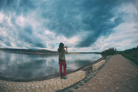 Evening marina. Sunset on the coast. A girl photographs the evening sea. A woman photographs a...
