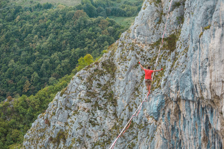 A man is walking along a stretched sling. Highline in the mountains. Man catches balance....