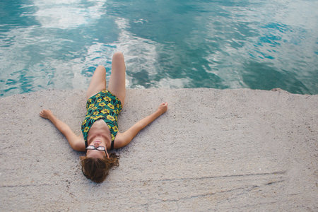 A woman is sunbathing on a beach. The girl in a bathing suit lies on the seashore. Holidays on the coast.の写真素材