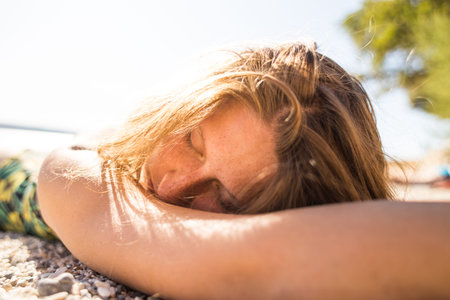 A woman is sunbathing on a beach. The girl in a bathing suit lies on the seashore. Holidays on the coast.の写真素材
