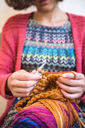 Woman crochets. Handwork. Crochet hook. Female hands closeup. Female hands hold the hook. Vintage carpet. Knitted plaid. Handmade. Home hobby.の写真素材