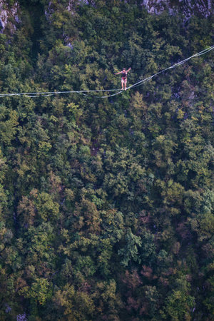 A man is walking along a stretched sling. Highline in the mountains. Man catches balance....