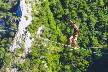 Highline in the mountains. A man goes on a stretched sling. Highliner is on the line. A tightrope...
