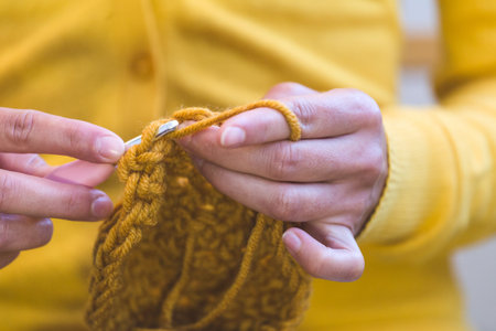 Woman crochets. Female hands close-up. The girl is engaged in needlework. A ball of yellow thread...
