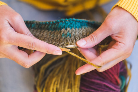 Female hands close-up. Young woman is knitting. Knitting needles and threads. Multi-colored yarn....