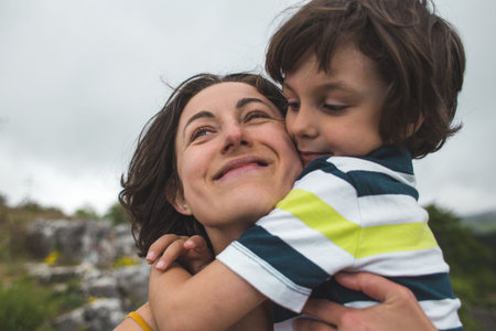 The boy hugs mom. Woman rests with her son in nature. The child kisses mom. Portrait of a mother and baby.の写真素材